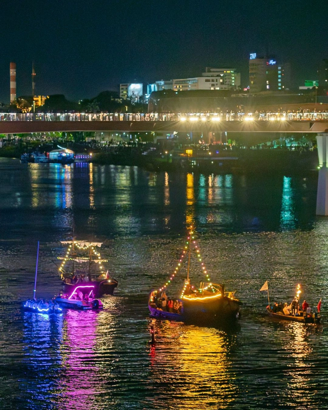 Kolorowo oświetlone łodzie płyną po Wiśle podczas nocnej parady Riverlights w Warszawie.