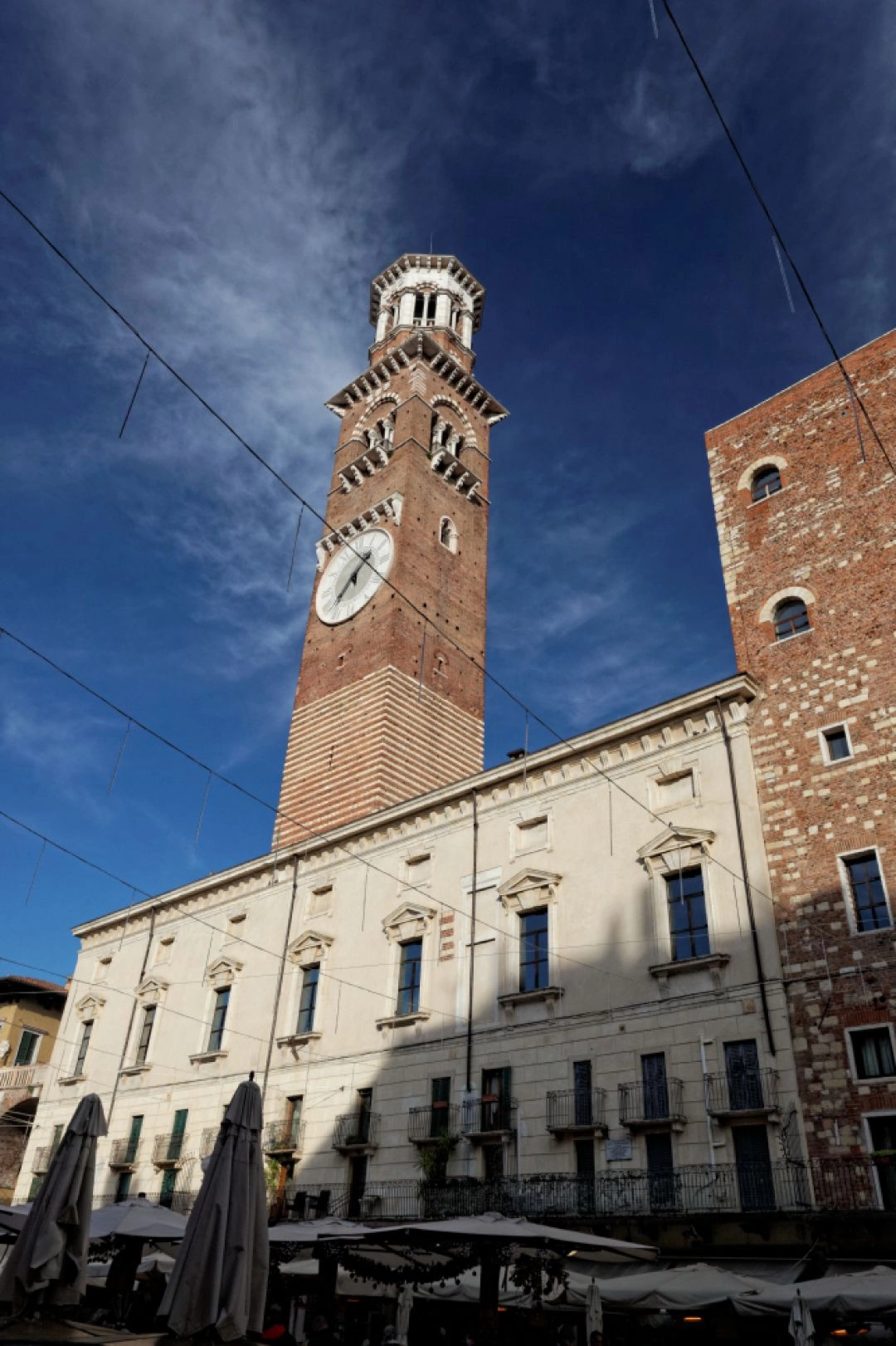 Wieża Lamberti w Weronie z zegarem i historyczną zabudową wokół placu.
