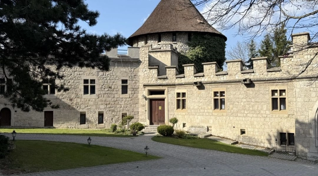 Dziedziniec zamkowy w Smolenicach z kamiennymi murami, okrągłą wieżą i brukowanym placem.