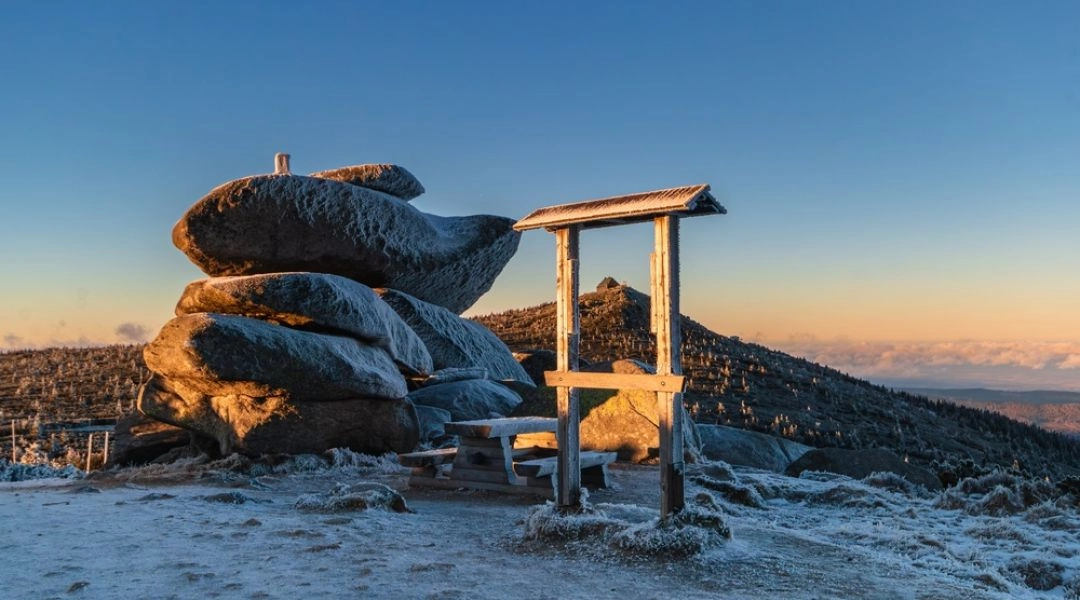 Karkonosze zimą – szczyt z charakterystycznymi skałami i widokiem na ośnieżone góry