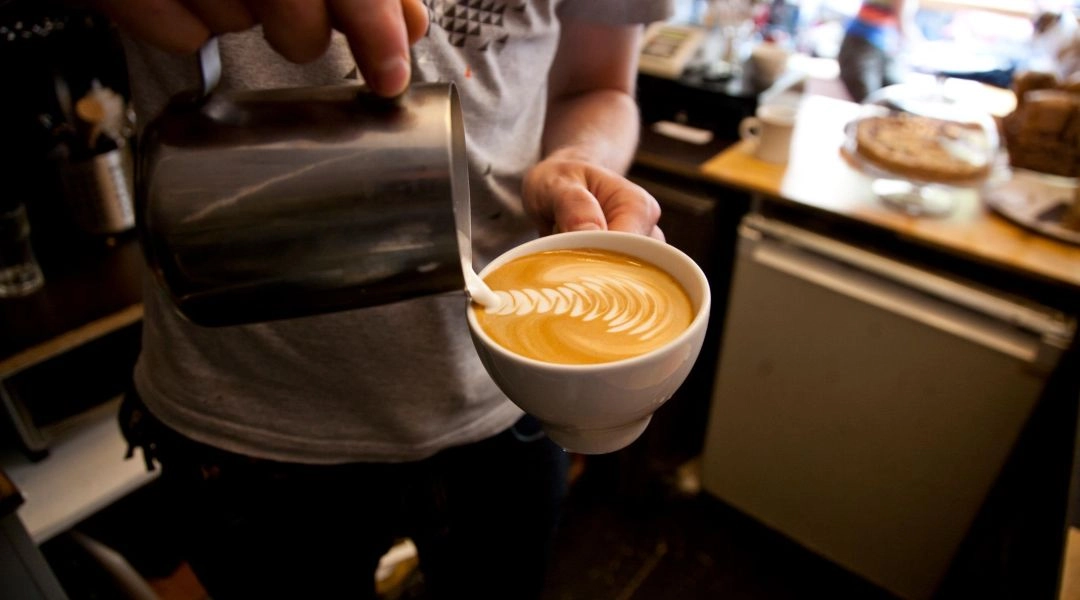 Barista nalewający kawę za barem w kawiarni Relaks w Warszawie.