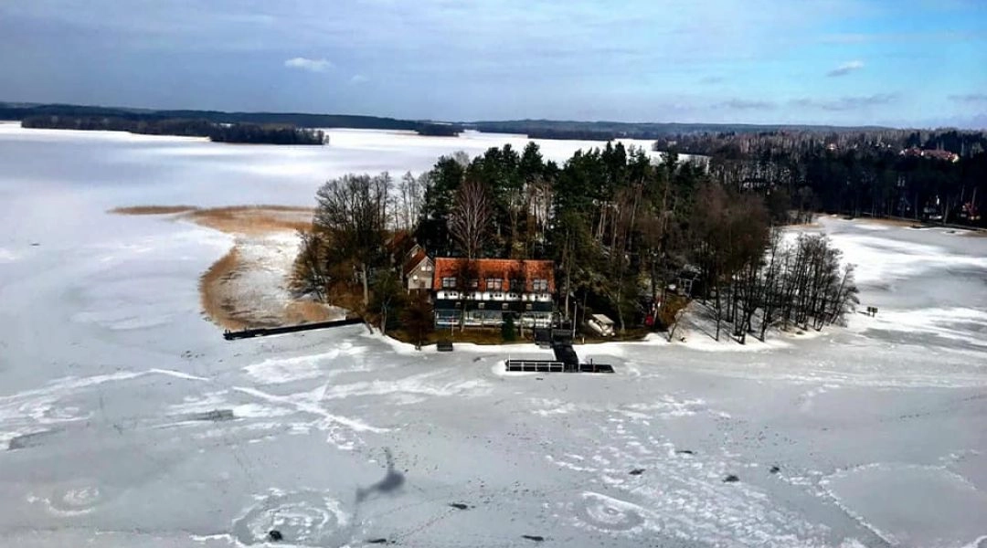 Widok z góry na Wyspę Brzozową na zamarzniętym jeziorze, zimowa sceneria.