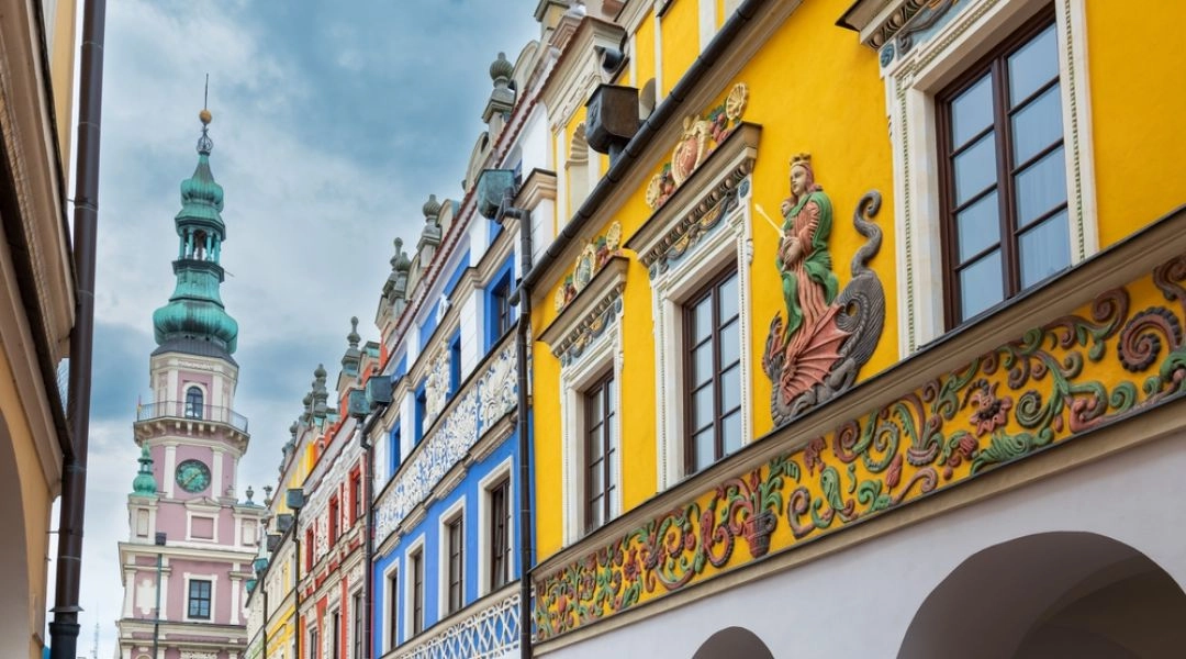 Kolorowe kamienice ormiańskie z bogato zdobionymi fasadami i wieża ratusza w Zamościu.