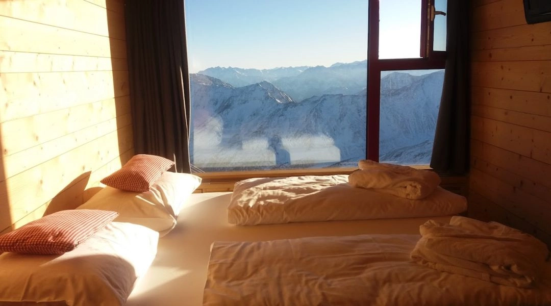 Wnętrze pokoju w Glacier Hotel Grawand oświetlone porannym słońcem z widokiem na góry