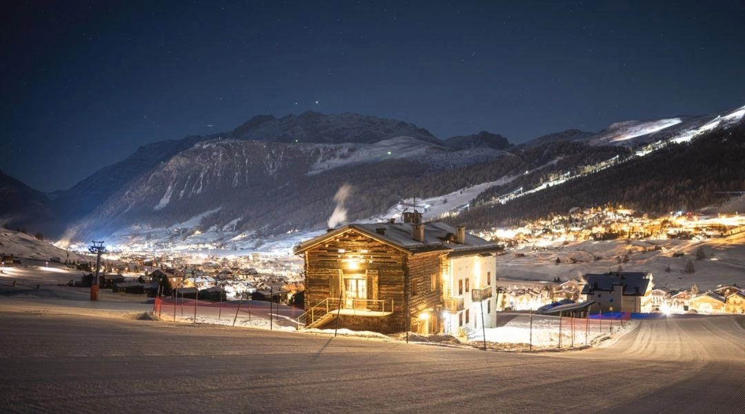Livigno nocą, oświetlone miasteczko i trasy narciarskie w alpejskiej dolinie