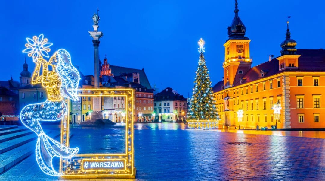 Świąteczne dekoracje na Placu Zamkowym w Warszawie: choinka, iluminowana syrenka i Zamek Królewski oświetlone w zimowy poranek.