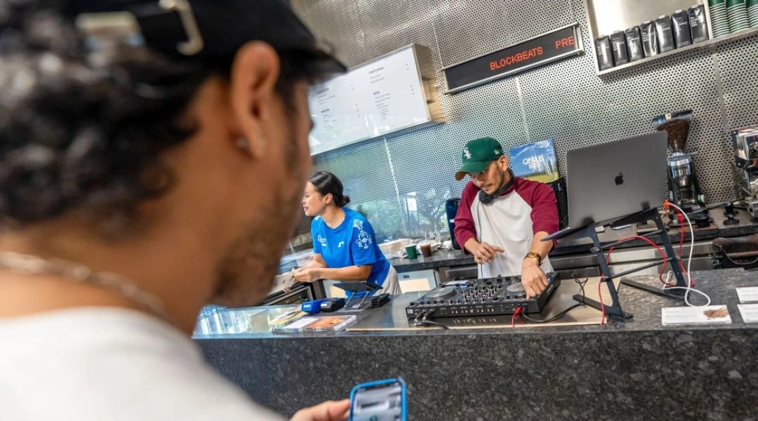 DJ grający muzykę elektroniczną przy konsoli ustawionej na barze kawiarni, w której odbywa się coffee rave.