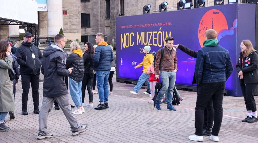 Uczestnicy Nocy Muzeów stoją przed scenografią wydarzenia ustawioną przy Pałacu Kultury i Nauki w Warszawie.