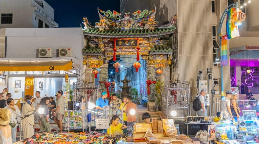 Tłum ludzi i stoiska nocnego targu na ulicy otoczonej kolorowymi kamienicami w Old Phuket Town