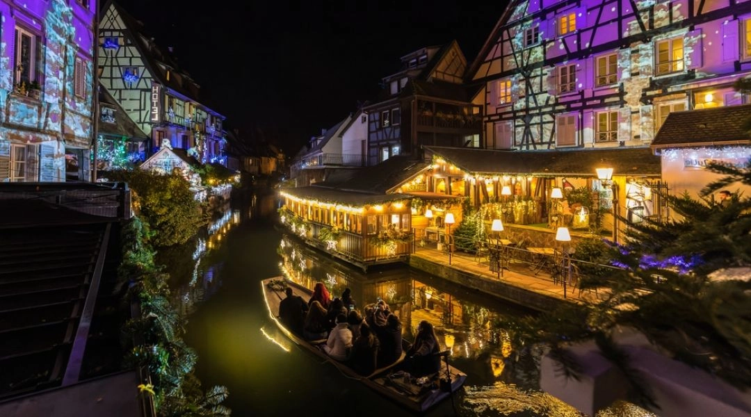 Colmar w czasie świąt, zabudowa nad kanałem Petite Venise z delikatnymi iluminacjami bożonarodzeniowymi.