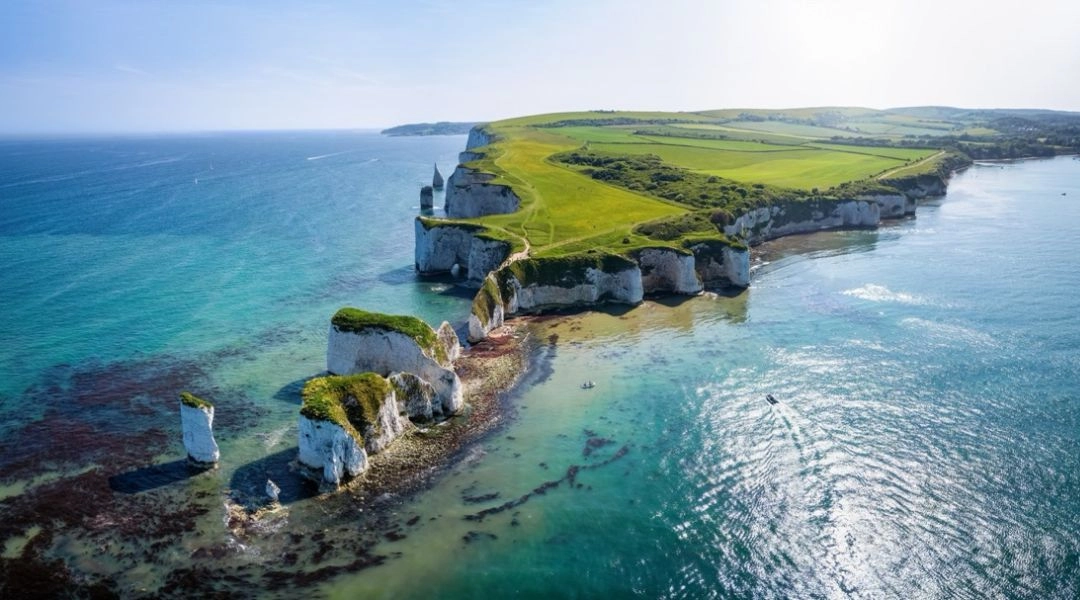 Białe klify nad turkusowym morzem na południowym wybrzeżu Anglii, zielone pola i widok z lotu ptaka.