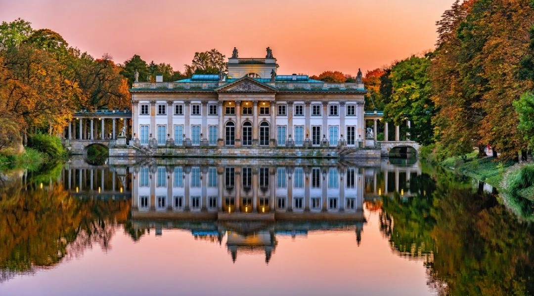 Pałac na Wyspie w Łazienkach Królewskich w Warszawie odbijający się w wodzie o zachodzie słońca.