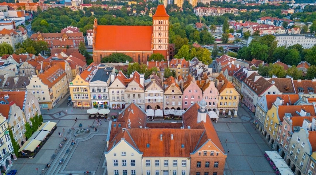 Stare Miasto w Olsztynie z lotu ptaka, z ratuszem, kolorowymi kamienicami i górującym nad zabudową kościołem.