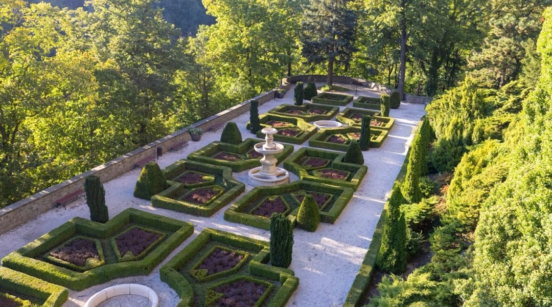 Geometryczne ogrody tarasowe z fontanną i przyciętymi żywopłotami przy Zamku Książ.