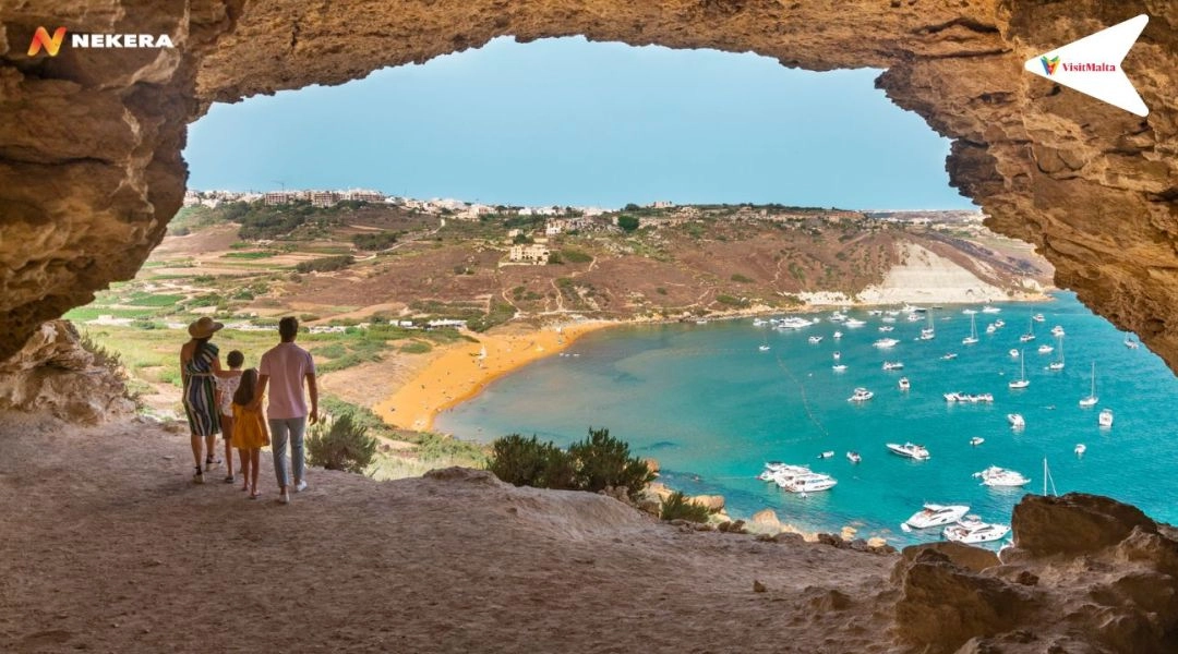 Plaża Ramla Bay na Gozo widziana z naturalnej groty, złoty piasek i zatoka z łodziami