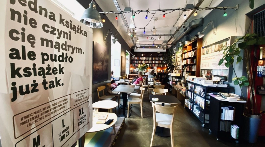 Wnętrze Wrzenia Świata w Warszawie z regałami książek i stolikami.