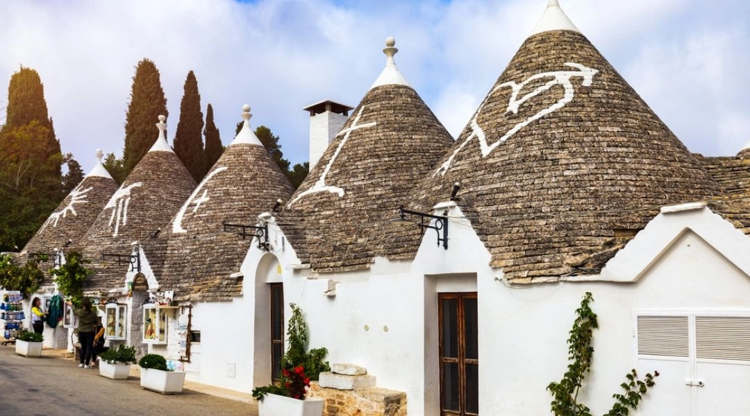 Tradycyjne białe domki trulli ze stożkowatymi kamiennymi dachami przy uliczce w Alberobello w Apulii.