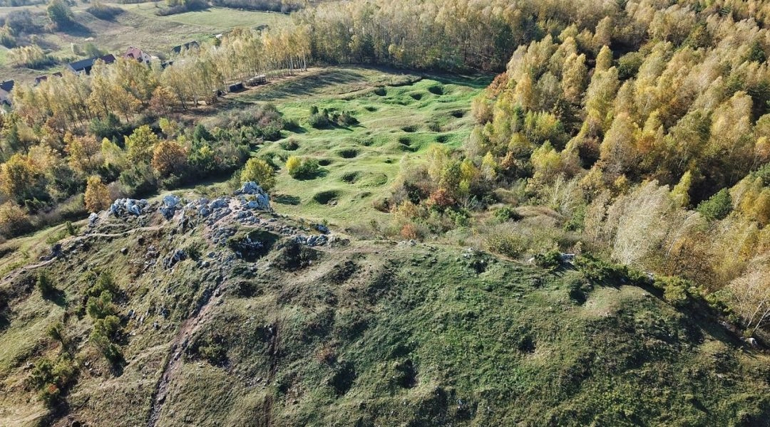 Widok z góry Miedzianka na pagórkowaty teren i ślady dawnej działalności górniczej w Geoparku Świętokrzyskim UNESCO.