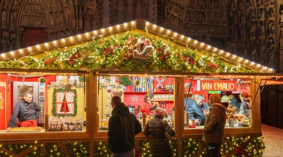 Kolorowe papierowe gwiazdy i lampiony oświetlające stoisko na jarmarku świątecznym w Warszawie.