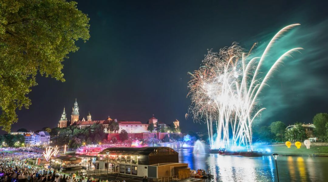 Wianki nad Wisłą w Krakowie z pokazem świateł nad rzeką i widokiem na Wawel nocą.