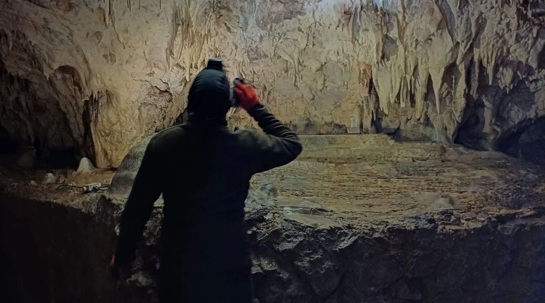 Turysta oglądający stalaktyty, stalagmity i jasne nacieki skalne we wnętrzu Jaskini Raj.