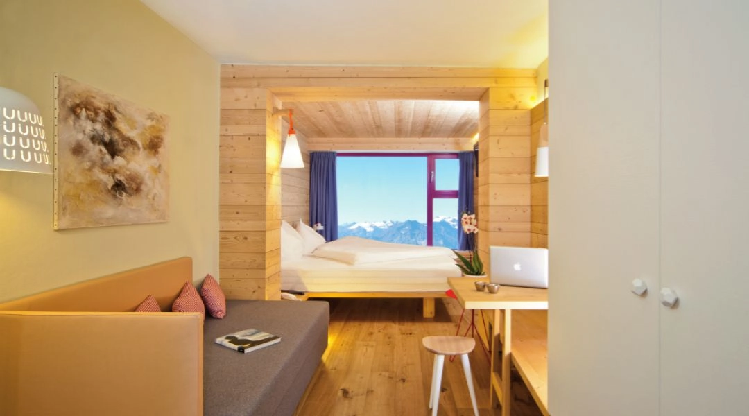 Pokój w Glacier Hotel Grawand z drewnianym wykończeniem i dużym oknem z widokiem na Alpy