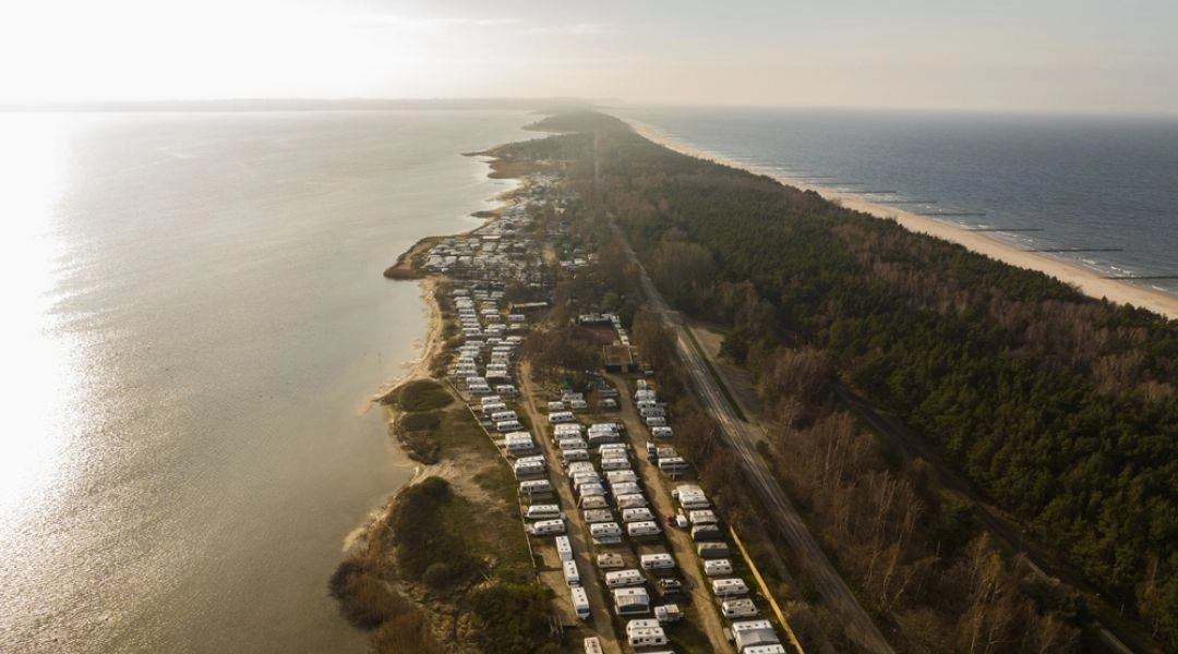 Widok z lotu ptaka na przyczepy campingowe ustawione nad Zatoką Pucką na Półwyspie Helskim