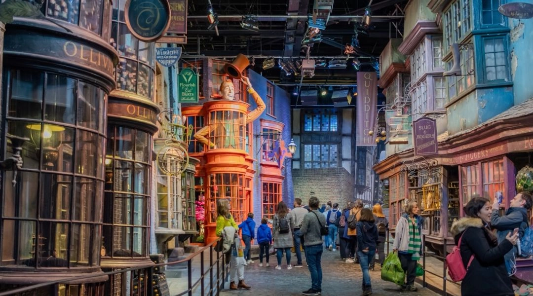 Zwiedzający na planie filmowym w Warner Bros. Studio Tour London, kolorowe witryny sklepów i dekoracje z „Harry’ego Pottera”.