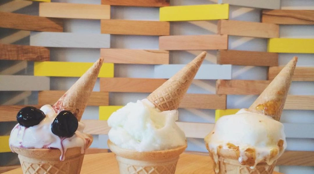 Trzy porcje lodów w rożkach ustawione na stole w lodziarni Jednorożec