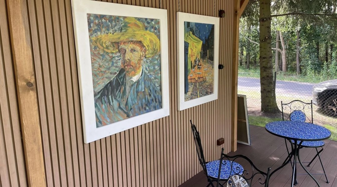 Reprodukcje dzieł Vincenta van Gogha zawieszone na drewnianej ścianie zadaszonego tarasu w Brzózkach.