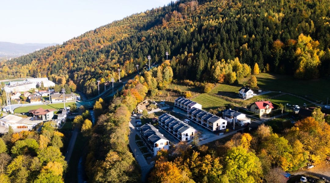 Jesienna panorama górskiej miejscowości otoczonej lasami w złotych barwach