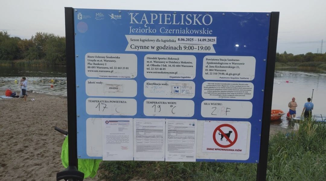 Tablica informacyjna kąpieliska nad Jeziorkiem Czerniakowskim z godzinami otwarcia, oceną jakości wody i regulaminem.