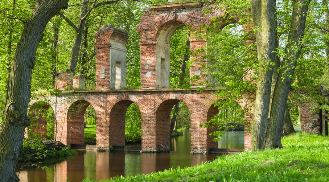 Park Romantyczny w Arkadii koło Łowicza z zabytkowym akweduktem nad wodą.