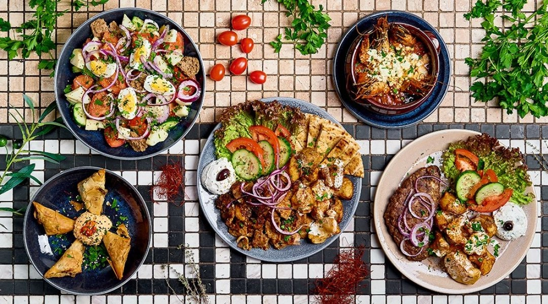 Greckie dania w nowoczesnej formie: mięso, pita i dodatki na talerzach na stole w Meze