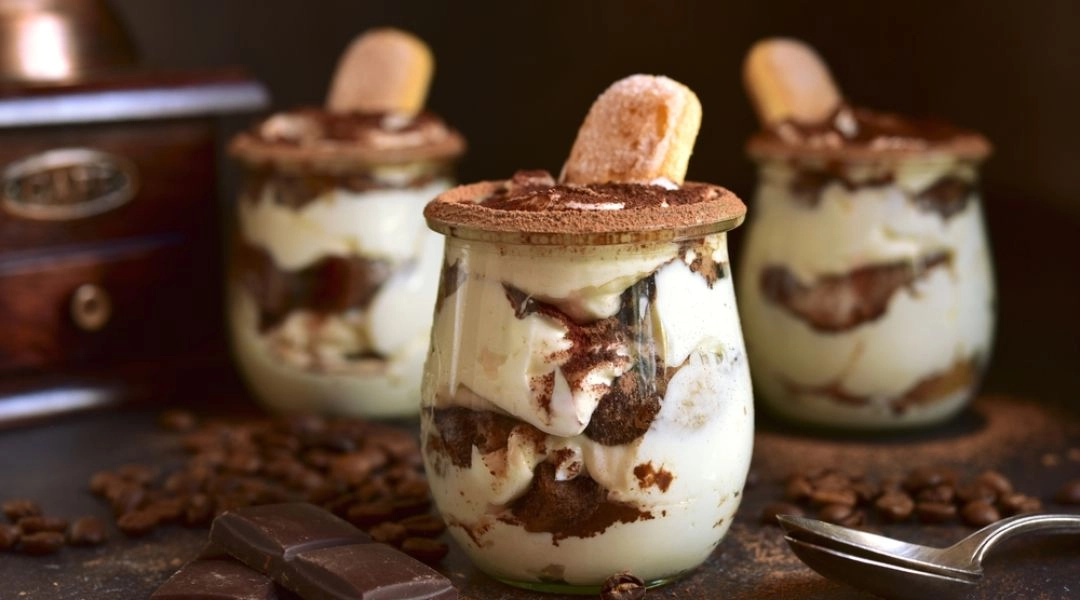 Tiramisu w słoiczkach z warstwami kremu i biszkoptów, podane jako deser na sylwestra.