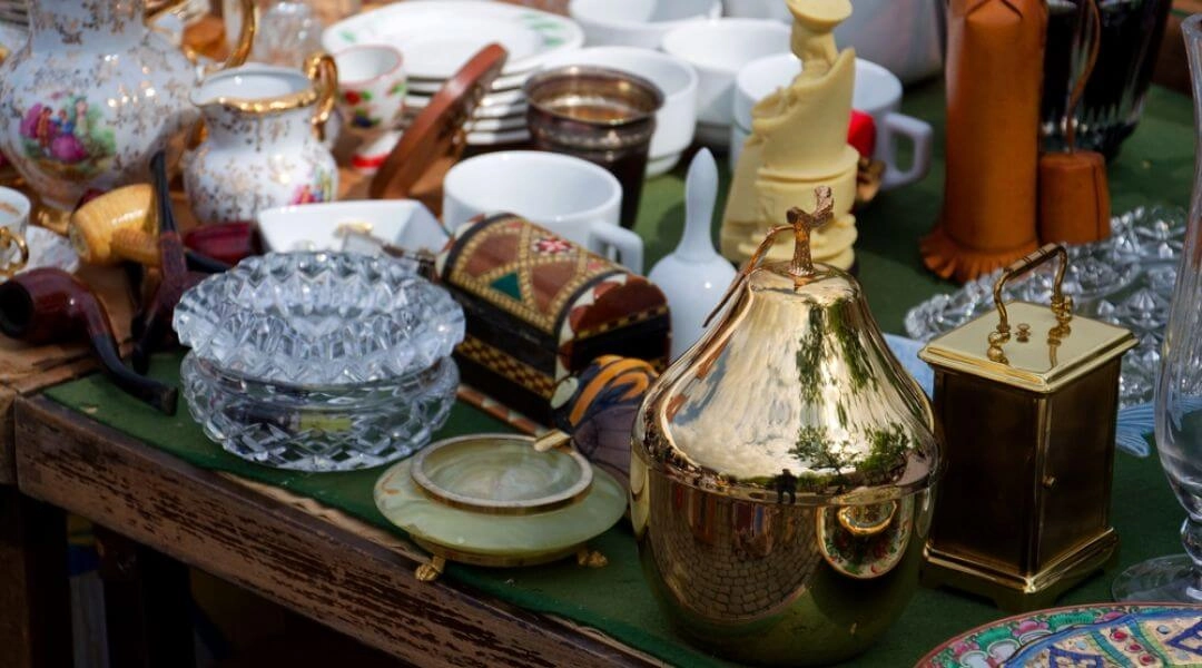 Stół z przedmiotami vintage: porcelana, szkło, metalowe naczynia i dekoracje na targach dizajnu.