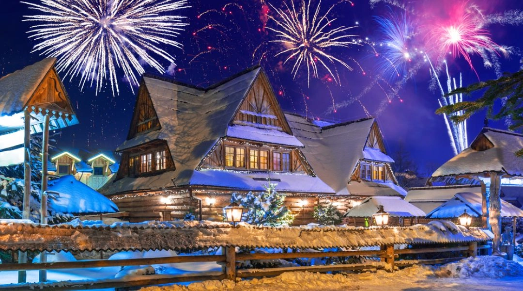Pokaz fajerwerków nad tradycyjną chatą góralską w Zakopanem.
