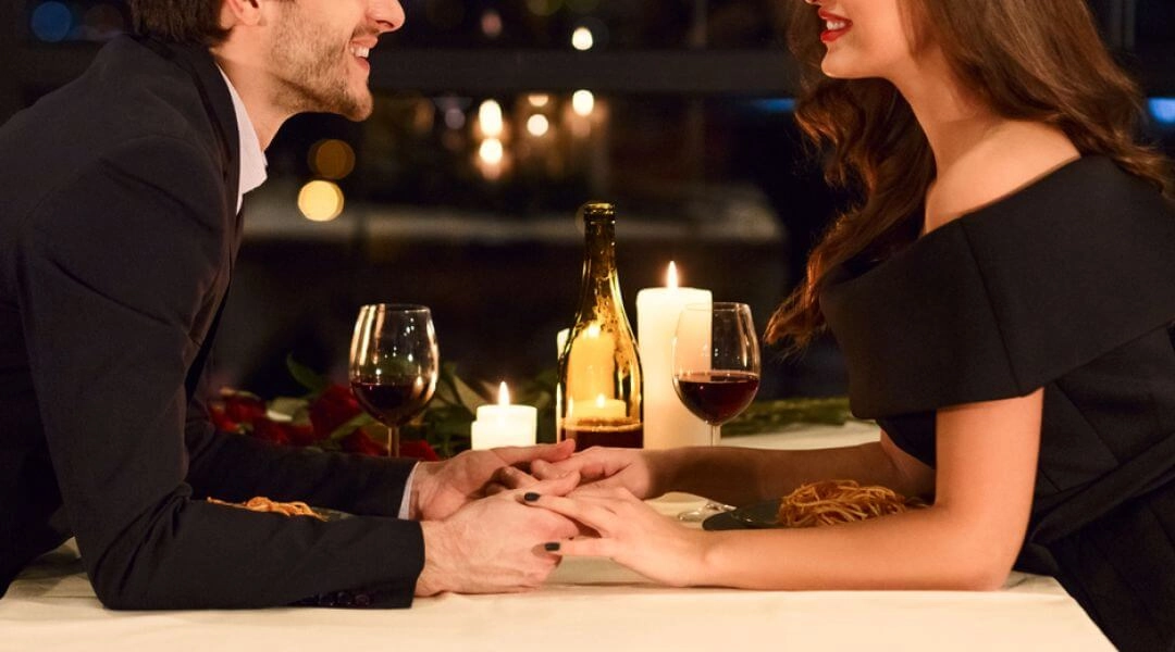 Para na romantycznej kolacji walentynkowej w restauracji, świeczki i wino.