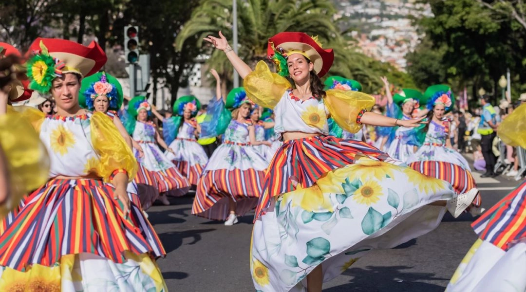 Tancerki w kolorowych sukniach ze wzorem słoneczników tańczą podczas Parady Kwiatowej w Funchal.