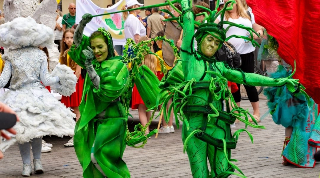 Performerzy w zielonych kostiumach występują podczas Parady Syrenki w Warszawie.