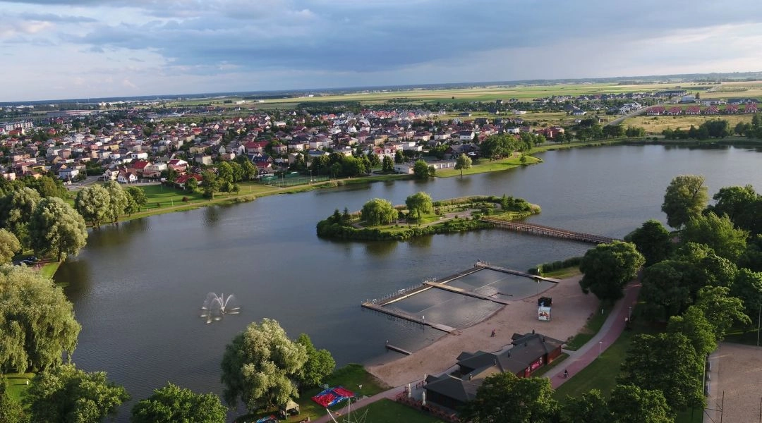 Zalew Arkadia w Suwałkach widziany z lotu ptaka, z kąpieliskiem, pomostami, zielenią i zabudową miasta w tle.