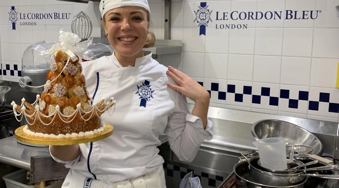 Oliwia Kupidłowska jako uczennica Le Cordon Bleu London w białym stroju cukierniczym prezentuje klasyczny francuski deser z karmelizowanego ciasta parzonego.