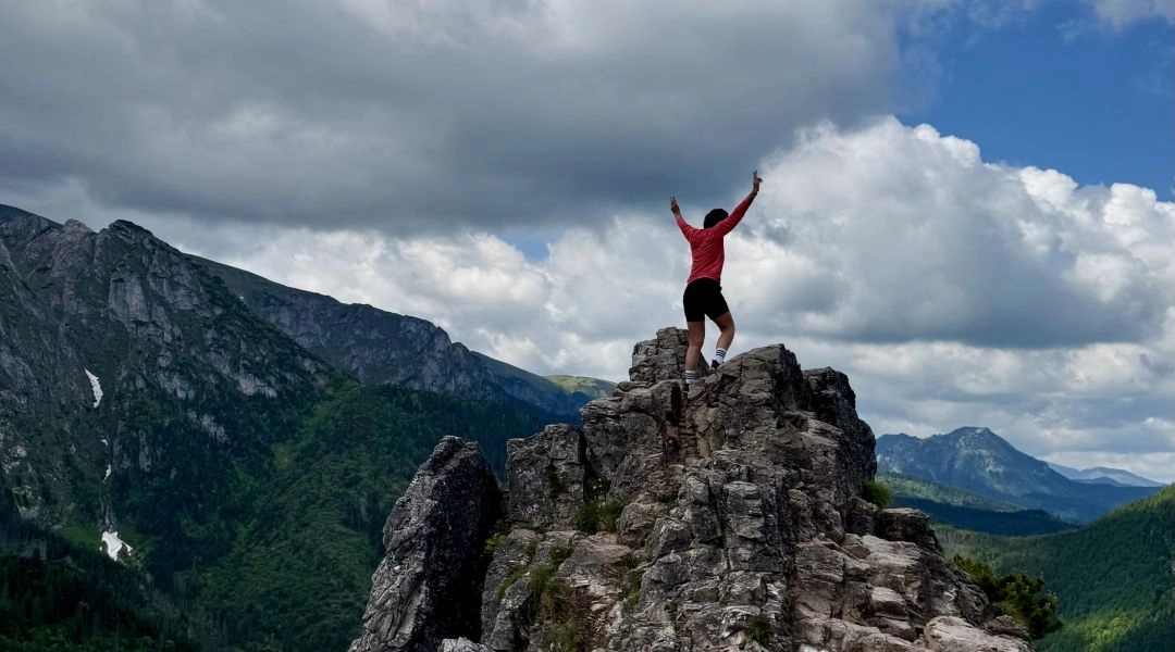 Autorka stojąca na skalistym wierzchołku Sarniej Skały z widokiem na Tatry i gęste chmury.