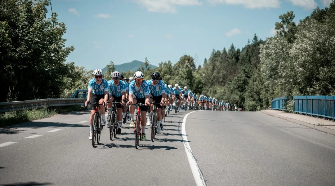 Duży peleton kolarzy szosowych jedzie przez górski krajobraz Orawy podczas Faster than a Train.