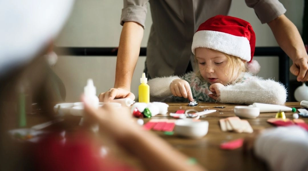 Dziecko wykonujące świąteczne dekoracje przy stole podczas warsztatów plastycznych.