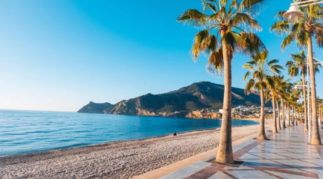 Nadmorska promenada z palmami przy plaży i spokojnym morzu w Hiszpanii