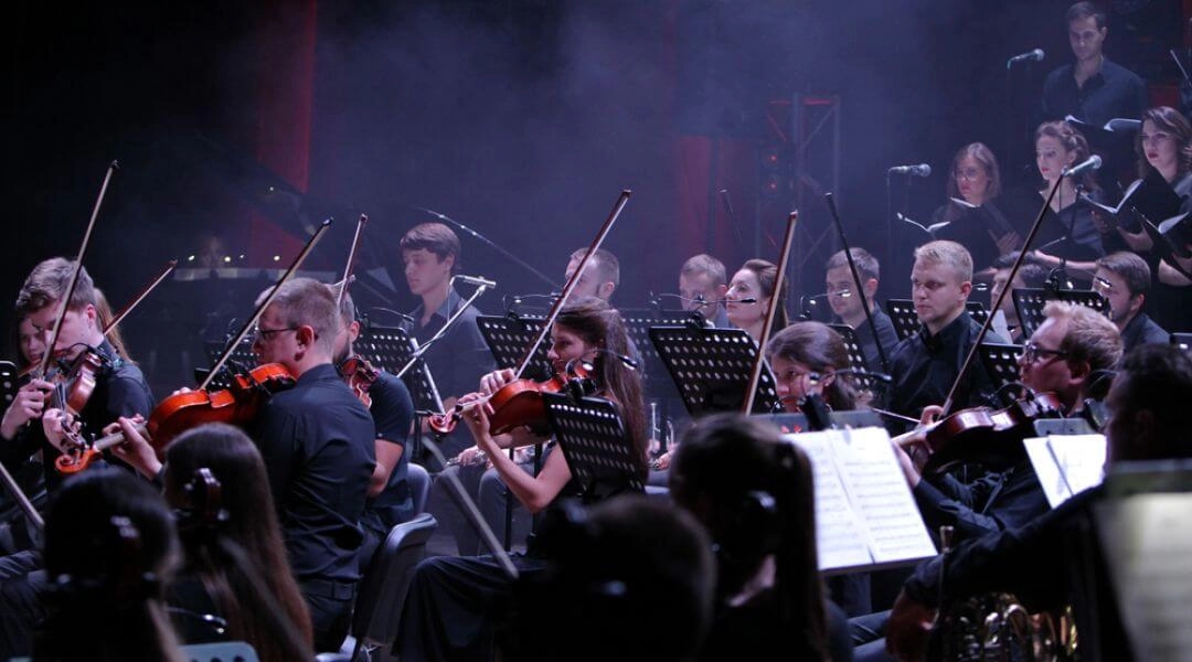 Orkiestra symfoniczna grająca podczas koncertu sylwestrowego, muzycy w czarnych strojach na scenie.