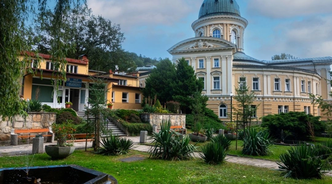 Zabytkowy budynek Zdroju Wojciech z charakterystyczną kopułą, widziany od strony ogrodu w Lądku-Zdroju.