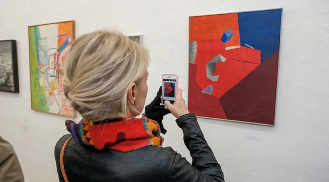 Zwiedzająca fotografuje obrazy podczas wystawy w Otwartej Pracowni w Krakowie.