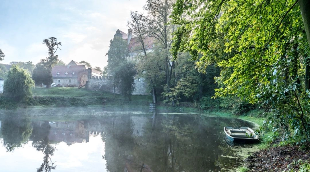 Jeden ze stawów przy Uroczysku Siedmiu Stawów i renesansowy zamek w tle